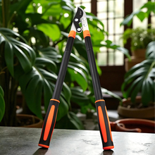 Load image into Gallery viewer, Gardening shears with orange handles on a table with plants in the background