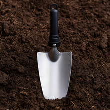 Load image into Gallery viewer, Silver garden trowel with black handle on dark brown soil
